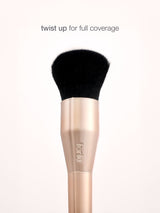Makeup brush with black bristle head and rose gold handle on a white background