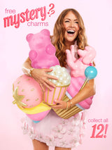 Woman cradles oversized pink novelty charms — gummy bear, popcorn tub, unicorn, lollipop — laughing in a pastel studio; promotional text reads free mystery? charms and collect all 12!