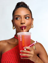 Woman holding a Dunkin' iced coffee cup with a straw against a plain background